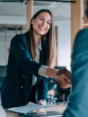 Business people shaking hands in the office. Group of business persons in business meeting. Three entrepreneurs on meeting in board room. Corporate business team on meeting in modern office. Female manager discussing new project with her colleagues. Company owner on a meeting with two of her employees in her office.